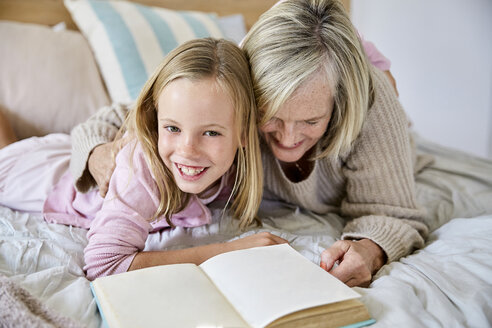 Porträt eines glücklichen kleinen Mädchens, das mit seiner Großmutter auf dem Bett liegt - SRYF00276