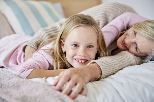 Portrait of happy little girl lying on the bed with her grandmother - SRYF00278