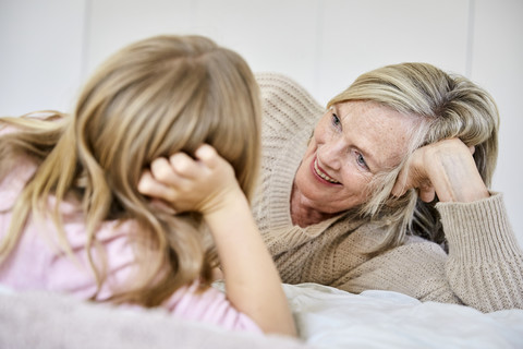 Ältere Frau entspannt sich mit ihrer Enkelin auf dem Bett, lizenzfreies Stockfoto