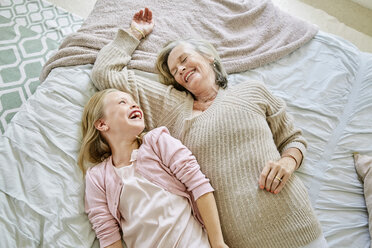 Little girl lying on the bed with her grandmother having fun - SRYF00283