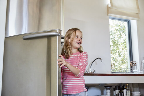 Lächelndes kleines Mädchen beim Öffnen des Kühlschranks - SRYF00296