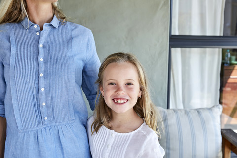 Porträt eines lächelnden kleinen Mädchens neben seiner Mutter auf einer Terrasse, lizenzfreies Stockfoto