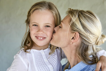 Porträt eines lächelnden kleinen Mädchens, das von seiner Mutter geküsst wird - SRYF00322