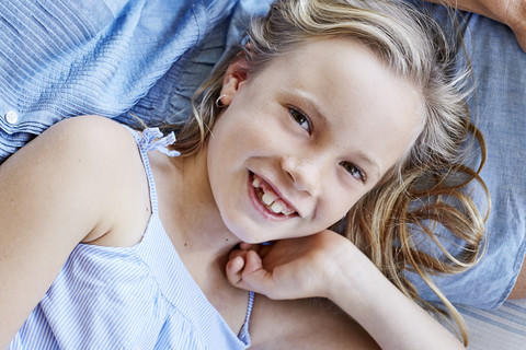 Porträt eines lächelnden kleinen Mädchens mit Zahnlücke auf dem Schoß der Mutter, lizenzfreies Stockfoto