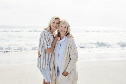 Senior woman and her adult daughter standing on the beach, embracing - SRYF00344