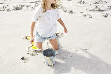 Little girl playing on the beach with bucket and shovel - SRYF00357