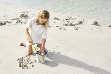 Little girl playing on the beach with bucket and shovel - SRYF00358