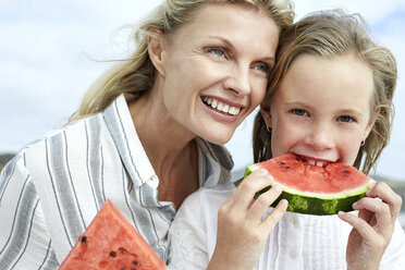 Mother and daughter eating water melon on the beach - SRYF00369