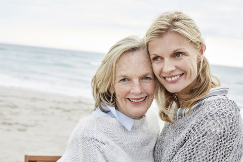 Mutter und Tochter umarmen sich am Strand, lizenzfreies Stockfoto