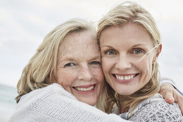 Mother and daughter embracing on the beach - SRYF00386