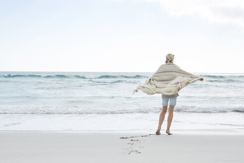 Mature woman enjoying the sea, wrapped in a blanket - SRYF00393