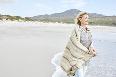 Mature woman enjoying the sea, wrapped in a blanket - SRYF00394