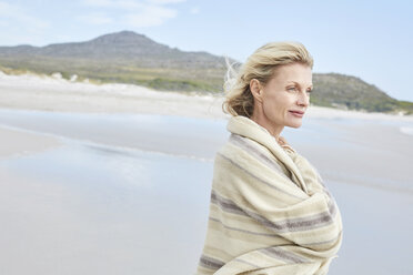 Ältere Frau genießt das Meer, eingewickelt in eine Decke - SRYF00395