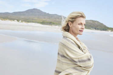 Mature woman enjoying the sea, wrapped in a blanket - SRYF00395