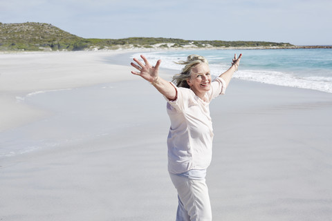 Ältere Frau hat Spaß am Strand, lizenzfreies Stockfoto