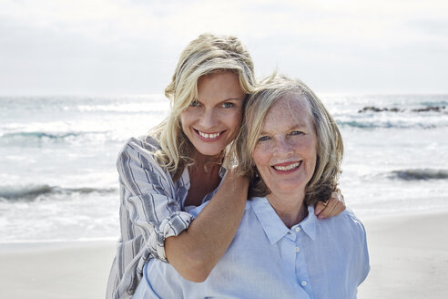 Mother and daughter embracing by the sea - SRYF00426