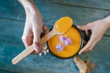 Close-up of man's hands eating creamed pumpkin soup - KIJF01428