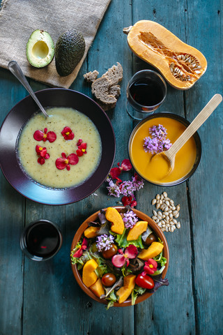 Bowls of creamed pumpkin soup and cream of avocado soup garnished with edible flowers stock photo