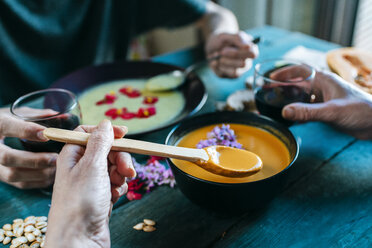 Hand einer Frau, die Kürbiscremesuppe isst und Rotwein trinkt - KIJF01435