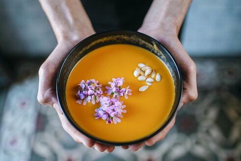 Männerhände mit Kürbiscremesuppe, garniert mit essbaren Blumen, Nahaufnahme - KIJF01437