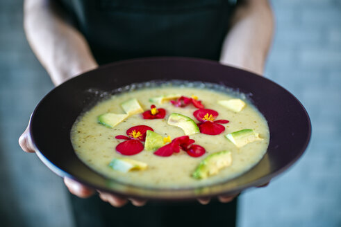 Männerhände mit Kürbiscremesuppe, garniert mit essbaren Blumen, Nahaufnahme - KIJF01438