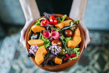 Männerhände halten eine Schüssel mit gemischtem Salat, garniert mit essbaren Blumen, Nahaufnahme - KIJF01439