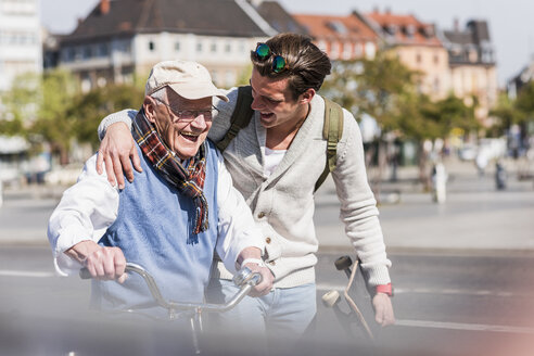 Glücklicher älterer Mann mit erwachsenem Enkel in der Stadt unterwegs - UUF10416