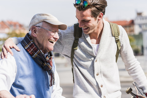 Happy senior man with adult grandson in the city on the move stock photo