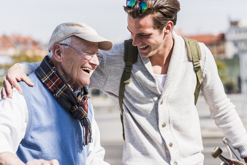 Glücklicher älterer Mann mit erwachsenem Enkel in der Stadt unterwegs - UUF10420