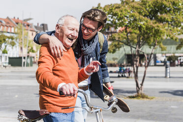 Glücklicher älterer Mann mit erwachsenem Enkel in der Stadt unterwegs - UUF10438