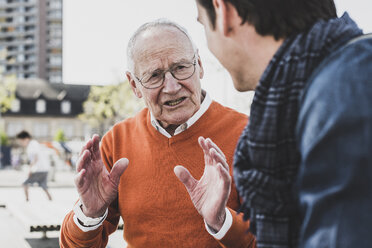 Senior man talking to adult grandson outdoors - UUF10446