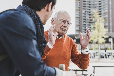 Senior man talking to adult grandson outdoors - UUF10447