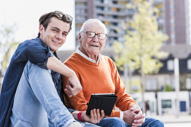 Porträt eines lächelnden älteren Mannes und eines erwachsenen Enkels mit Tablet - UUF10453