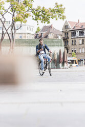 Young man with bicycle in the city using cell phone - UUF10463