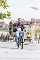 Young man with bicycle in the city holding cell phone - UUF10464