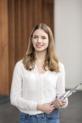 Portrait of smiling young businesswoman with notebook and clip board - PESF00533