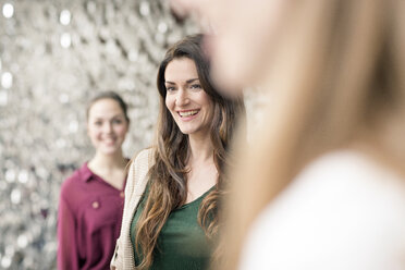 Porträt einer lachenden Geschäftsfrau mit Mitarbeitern in einem Foyer - PESF00540