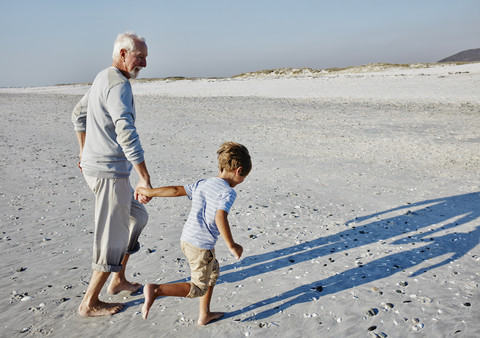 Grandfather and grandson strolling on the beach stock photo