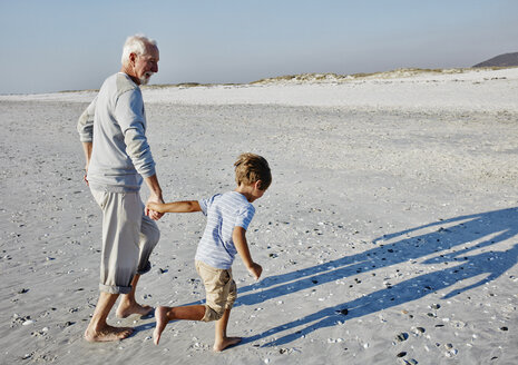 Grandfather and grandson strolling on the beach - RORF00755