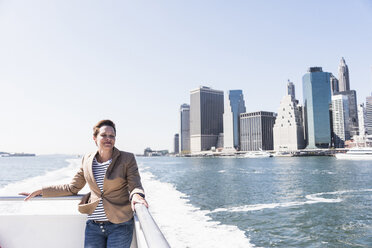 USA, New York City, Frau auf Fähre mit Skyline von Manhattan im Hintergrund - UUF10477