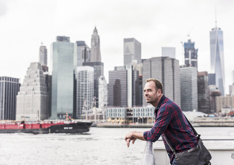 USA, New York City, Mann auf Fähre mit der Skyline von Manhattan im Hintergrund - UUF10482