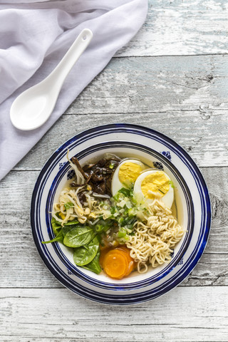 Schüssel Ramen-Suppe mit Spinat, Karotten, gekochtem Ei, Bambussprossen und Pilzen, lizenzfreies Stockfoto