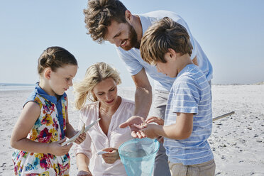 Glückliche Familie mit Tauchnetz am Strand - RORF00770