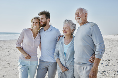 Lächelndes Seniorenpaar mit erwachsenen Kindern am Strand, lizenzfreies Stockfoto
