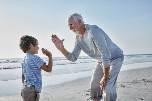 Grandfather and grandson high fiving on the beach - RORF00793