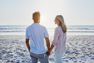 Paar hält Hände am Strand bei Sonnenuntergang - RORF00805