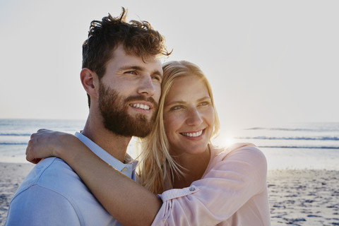 Smiling couple on the beach at sunset stock photo