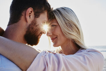 Smiling couple hugging on the beach at sunset - RORF00814