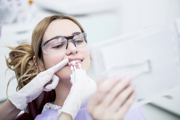 Frau beim Zahnarzt bei der Auswahl der Farbe für die Zahnaufhellung - WESTF22936