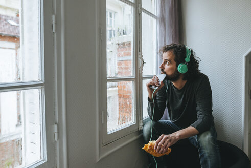 Man listening music with headphones and smartphone at home - KIJF01441